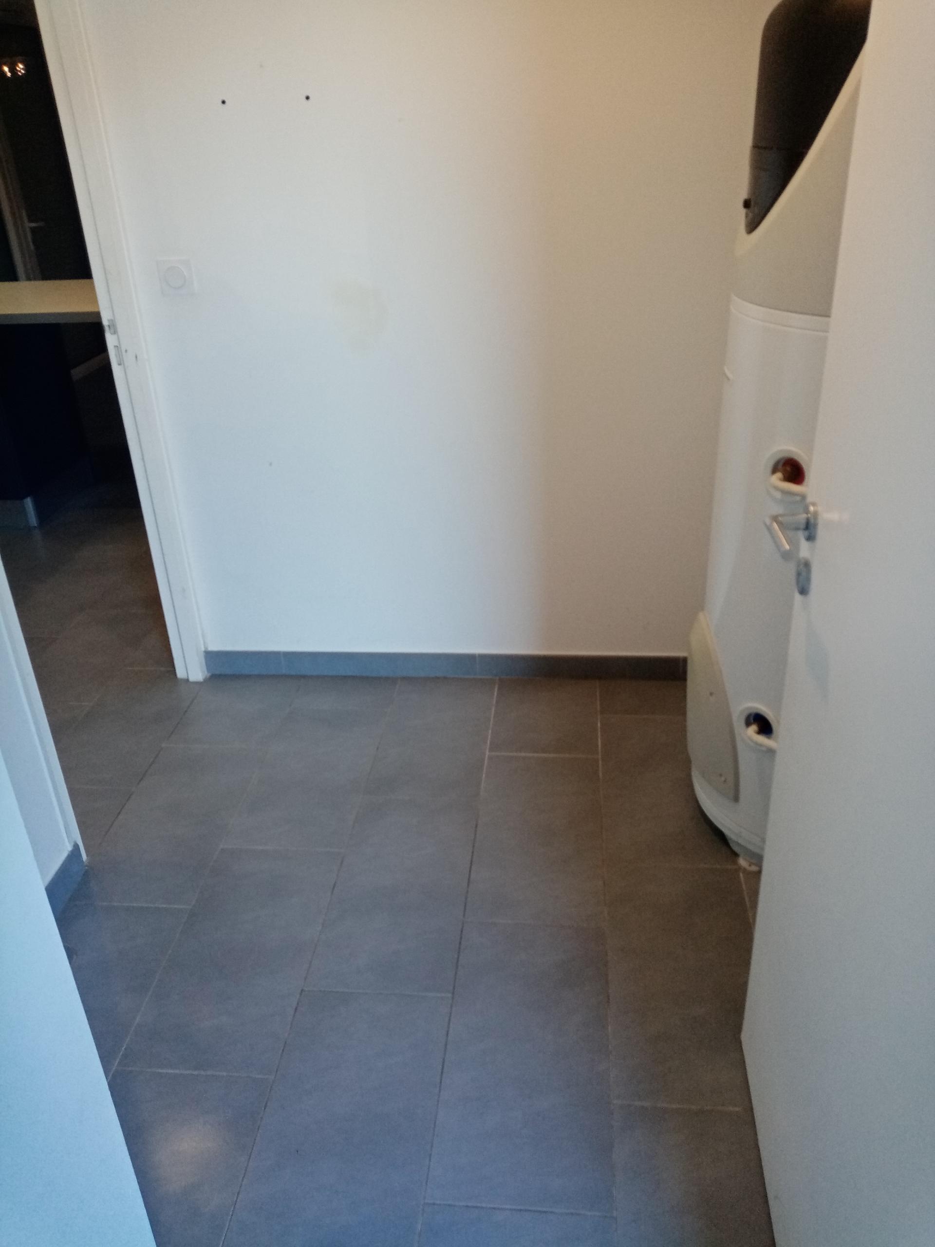 Local technique — chauffe-eau, sol carrelé, mur propre